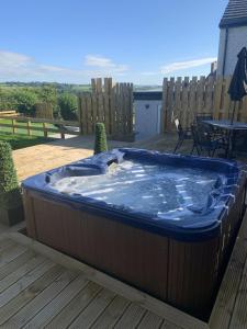 un jacuzzi en una terraza con una mesa en Luxury Cottage, views of the Lakes with Hot Tub en Cockermouth