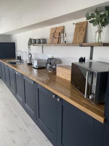 a kitchen with blue cabinets and a counter with a microwave at Luxury Cottage, views of the Lakes with Hot Tub in Cockermouth