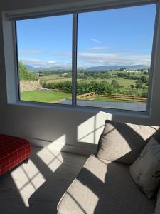 a living room with a couch and a large window at Luxury Cottage, views of the Lakes with Hot Tub in Cockermouth