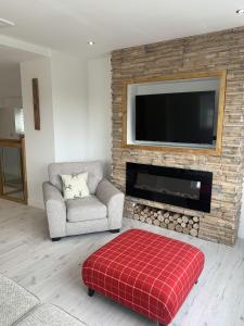 a living room with a fireplace with a flat screen tv at Luxury Cottage, views of the Lakes with Hot Tub in Cockermouth