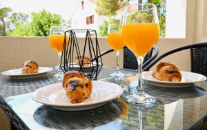 a table with plates of food and glasses of orange juice at Adorable Holiday Apartment in Malinska