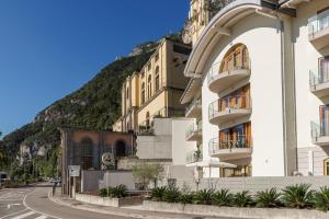 un bâtiment situé dans une rue en face d'une montagne dans l'établissement Exclusive Suites Riva, à Riva del Garda