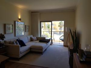 a living room with a white couch and a sliding glass door at JARDINS DA MARINA APARTMENT Ai in Albufeira