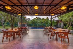 een restaurant met houten tafels en stoelen en een zwembad bij Atha Resort in Sigiriya