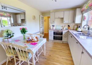 a kitchen with a table with chairs and a sink at Curlew Cottage in Langham