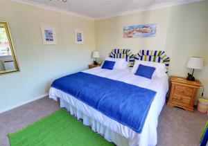 a bedroom with a large bed with blue and white sheets at Curlew Cottage in Langham