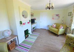 Curlew Cottage في Langham: غرفة معيشة مع أريكة وكرسي