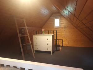 a room with a ladder and a dresser in a attic at Szitakötő vendégház in Mártély