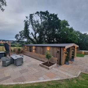 un patio con un edificio con mesa y sillas en Harewell wood cabin, en Pateley Bridge