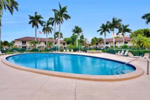a large swimming pool with chairs and palm trees at Idyllic condo with brief walk to beach and restaurants in Marco Island