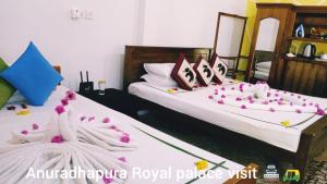 two beds in a room with pink flowers on them at Oleena Home Stay in Habarana