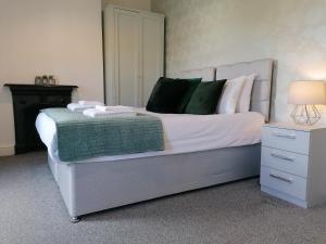 um quarto com uma cama com lençóis brancos e almofadas verdes em Ermine Rd Hoole - Period Victorian House by Rework Accommodation em Chester