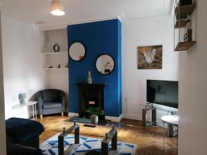 uma sala de estar com uma parede azul e uma televisão em Ermine Rd Hoole - Period Victorian House by Rework Accommodation em Chester