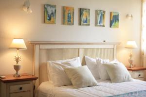 ein Bett mit weißen Kissen und Gemälden an der Wand in der Unterkunft Starfish Beach House in São Pedro de Muel