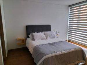 a bed in a bedroom with a large window at Modern apartment in new building. in Bogotá