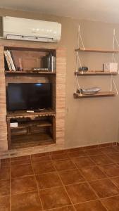 ein Wohnzimmer mit einem Flachbild-TV und Regalen in der Unterkunft Casa Zapatero en Somontano in Salas Bajas
