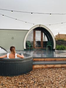 a woman sitting in a hot tub in front of a building at The Pods at Streamvale in Gilnahirk