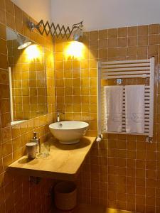 a yellow tiled bathroom with a sink and a mirror at B&B Santa Caterina in Acquaviva Picena