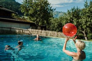 a woman playing with a red ball in a swimming pool at Aparthotel Hummerau in Alpbach