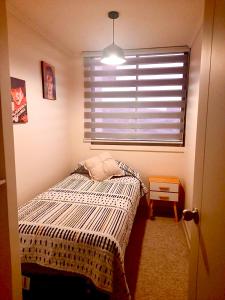 a small bedroom with a bed and a window at Departamento VIP vista al Mar y Ciudad in Valparaíso