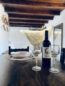 a bottle of wine and two wine glasses on a table at Lindia Athena Traditional House in Karpathos