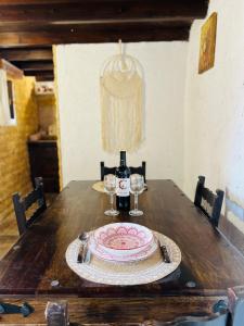 a wooden table with a plate and a bottle of wine at Lindia Athena Traditional House in Karpathos +6 photos