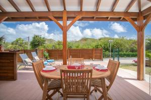 un tavolo e sedie in legno su un patio di Bungalow Pom 1, piscine, à 5 min des plages a Le Vauclin