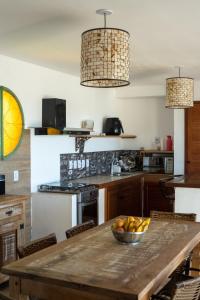 a kitchen with a wooden table with a bowl of fruit on it at Morada do Sol Guest House 2 in Búzios