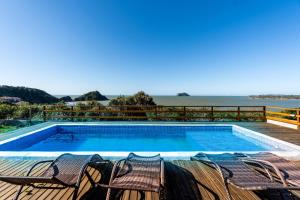 a swimming pool with chairs and the ocean in the background at Morada do Sol Guest House 2 in Búzios