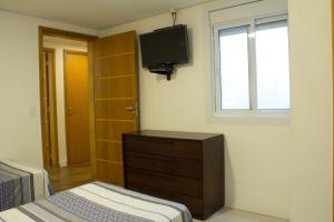 1 dormitorio con tocador y TV en la pared en Pousada Jardim Paulista, en São Paulo