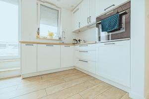 a kitchen with white cabinets and a wooden floor at Apartament Szlachecka in Warsaw