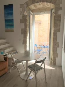 - une table et des chaises dans une chambre avec fenêtre dans l'établissement La Terrazza sul mare - Dimora di Charme, à Giovinazzo