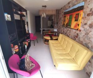 sala de estar con sofá amarillo y sillas rosas en Confortable apartamento en el corazón del eje cafetero, en Armenia