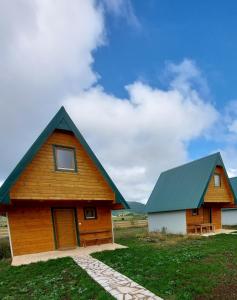 a wooden house with a green roof on a field at Vule bungalovi in Žabljak