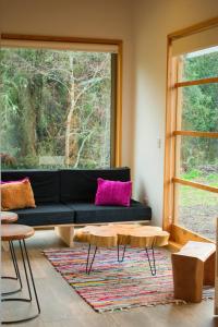 a living room with a black couch and a window at Cabaña a pasos del río rodeada de un hermoso entorno nativo natural in Villarrica