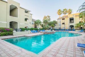 a swimming pool with blue chairs next to a building at o STUNNING CONDO MINUTES FROM GORGEOUS BEACHES o in Clearwater