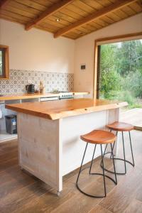 a kitchen with a counter and two stools at a island at Cabaña a pasos del río rodeada de un hermoso entorno nativo natural in Villarrica