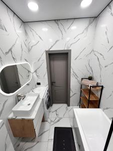 Un baño blanco con dos lavabos y un espejo. en ЖК на Исы Байзакова, en Pavlodar