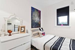 a bedroom with a bed with a dresser and a mirror at Modern 2 Bedroom Apartment in Hoxton in London