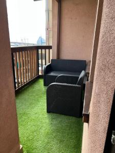 a balcony with green grass and a couch on a balcony at Apartament Portowy in Hel