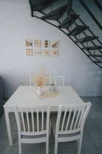 a white dining room table with two white chairs at Meraki Homestay Kanali in Kanali
