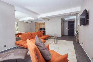 uma sala de estar com sofás laranja e uma televisão em Bel Air Crest em Accra