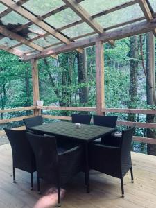 una mesa y sillas en un porche con pérgola en Voronins Retreat House, en Lumshory