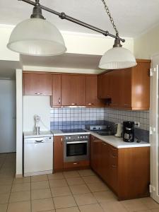 een keuken met bruine kasten, witte apparaten en 2 verlichting bij KomiVillas in Lilikás