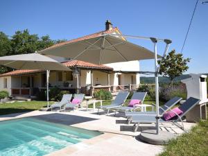 Viré的住宿－Les Poujols 6 Pers，一组椅子和一把遮阳伞,位于游泳池旁