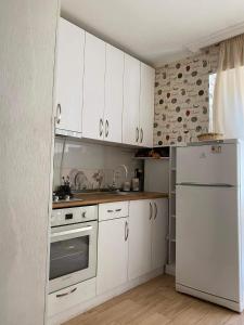 a kitchen with white cabinets and a white refrigerator at Cosy Home in Rustavi