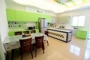 a kitchen with green cabinets and a table and chairs at Edinburgh 16 Inn in Hengchun South Gate