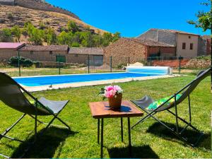 two lawn chairs and a table with flowers on it at HOTEL RURAL LA HUERTA in Montejo de la Vega de la Serrezuela +6 photos