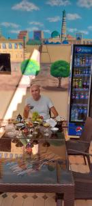 a man sitting at a table in front of a drink machine at Khiva Khan in Khiva