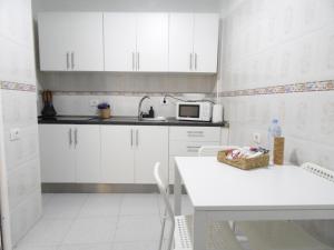 a kitchen with white cabinets and a table and a microwave at Sea House Tajao in La Mareta